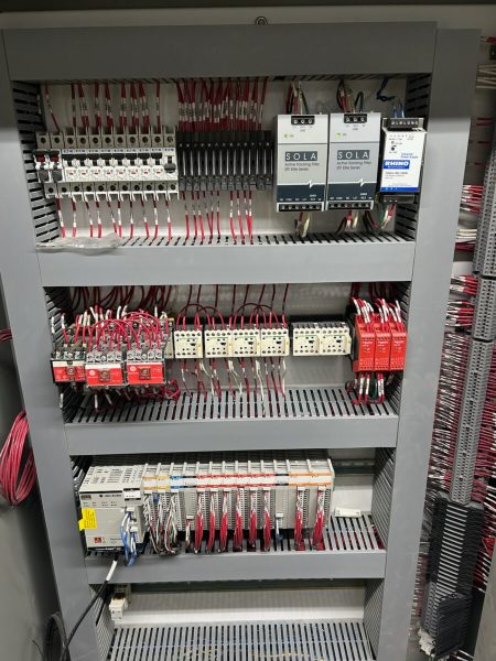 An industrial electrical control panel with circuit breakers, relays, power supplies, and organized wiring.