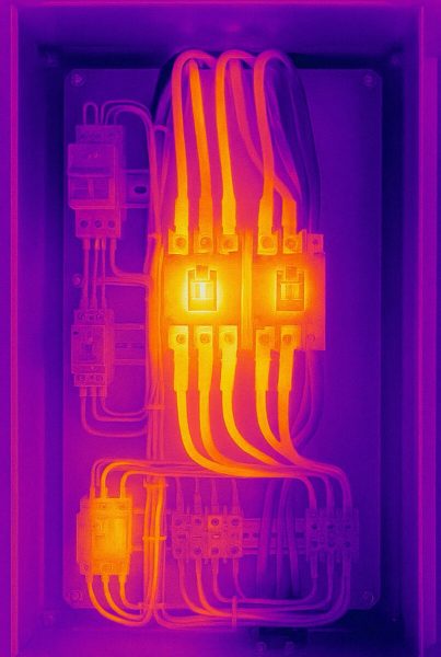 Thermal image of an electrical panel showing heat distribution, with hotspots at two central circuit breakers.
